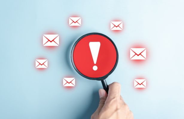 warning exclamation mark in a red magnifying glass surrounded by red outlined envelopes