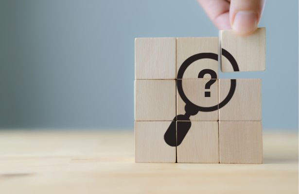 wooden cubes with illustration of a magnifying glass analyzing a question mark sign