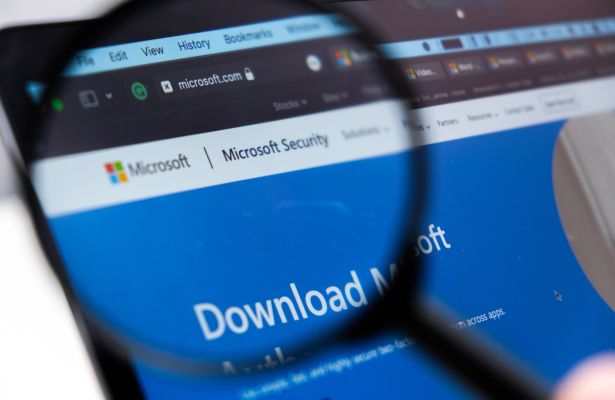 microsoft security logo enlarged through a magnifying glass on a laptop screen