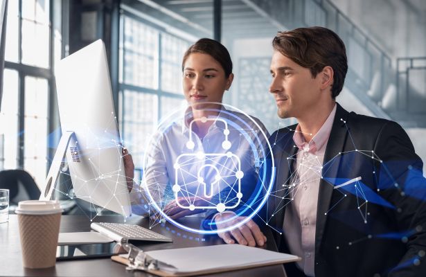 Two business professionals sitting at a computer, with a image of a digital padlock super imposed